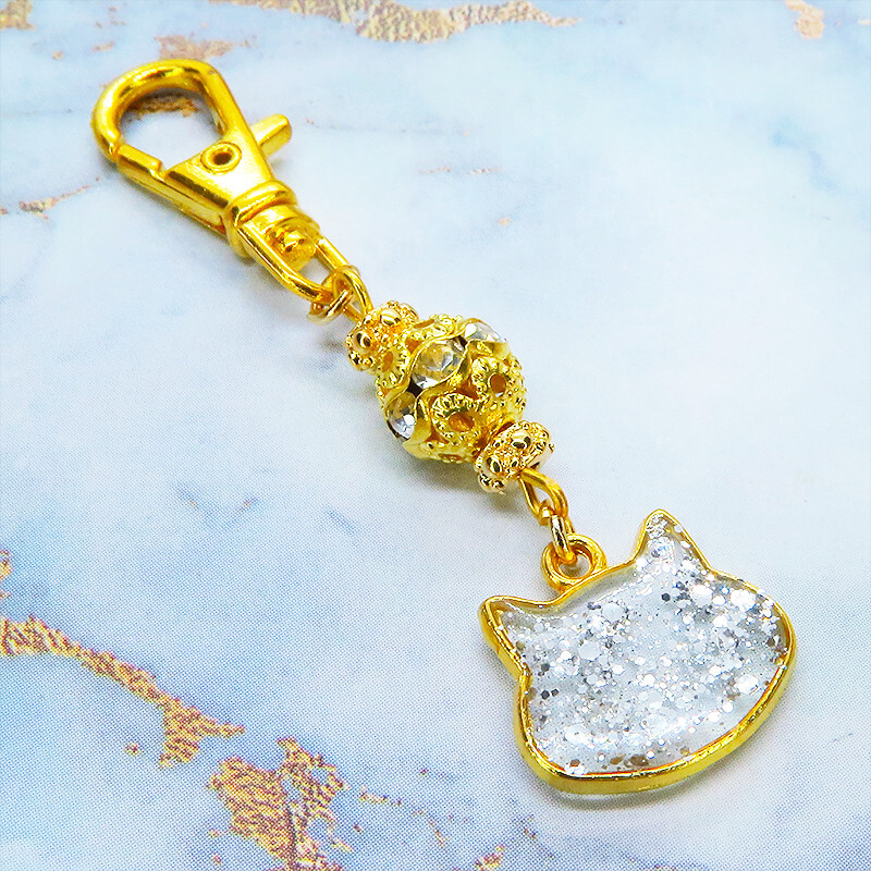 ゴールドカラー 猫フェイスモチーフのクリアカラーレジンのキーホルダー ラインストーン入りメタルビーズ 金具変更可拍卖