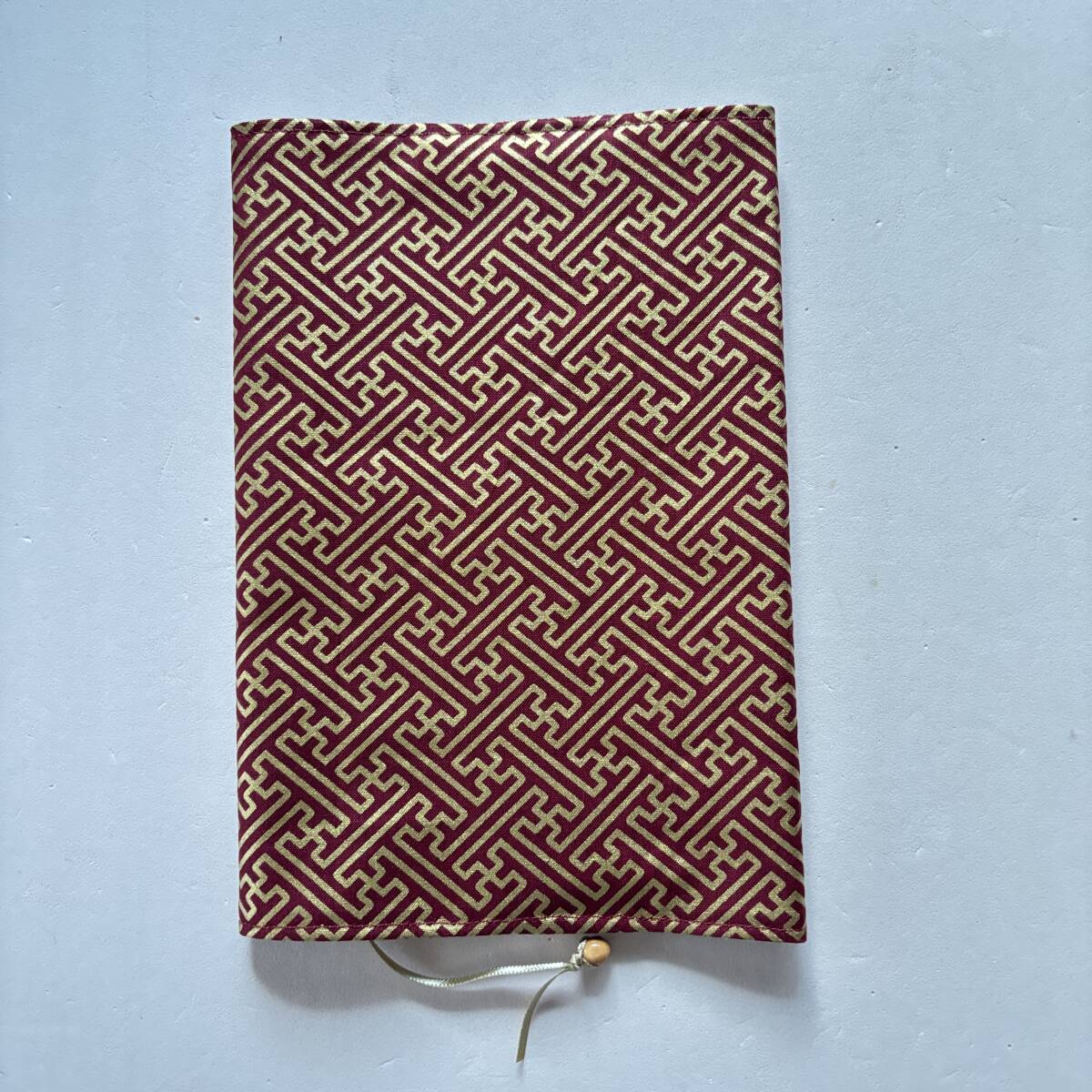 単行本サイズのブックカバー えんじ色地に金色の紗綾形模様拍卖