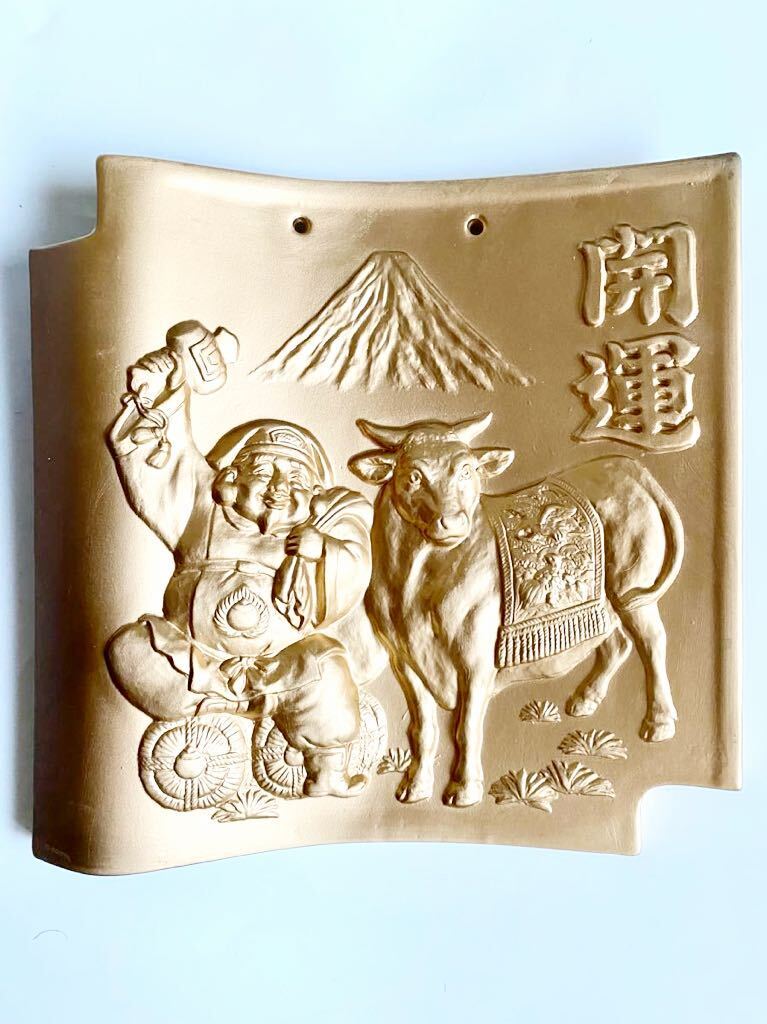 干支瓦(丑年) 縁起物 打ち出の小槌を振る大黒様と飾り馬具の牛 金彩 飾り瓦拍卖