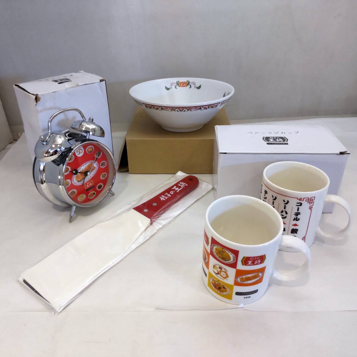 Y012907■餃子の王将 グッズ4点 目覚まし時計 どんぶり鉢 餃子返しヘラ ペアマグカップ 使用感なし 箱つぶれあり■